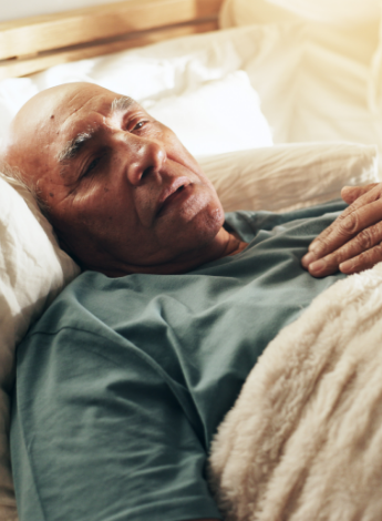 A older man lying in a hospital bed.